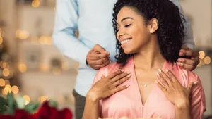 Young black guy wearing necklace on his happy woman