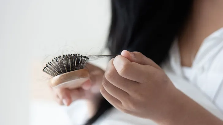 Vrouw haalt haar uit haar haarborstel.