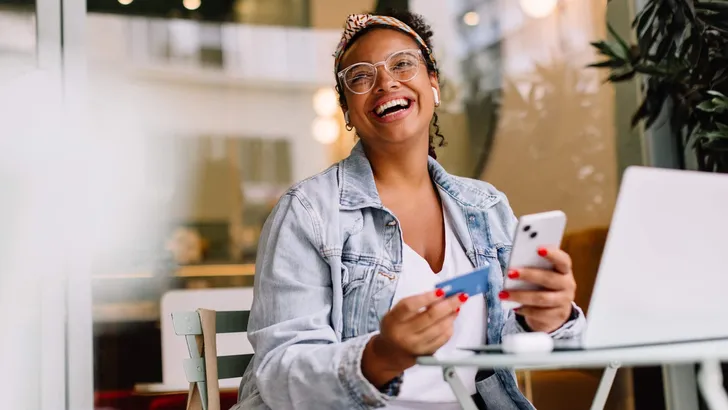 Young woman using smartphone for online shopping in a coffee shop