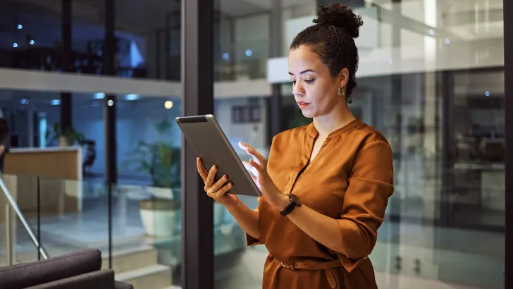 Tablet, working at night and woman employee planning or typing digital strategy in an office. Business, tech and online employee using technology to do internet and web research for a startup project