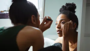 Vrouw die voor de spiegel eyeliner aanbrengt. Deze eyeliner-truc is perfect voor hooded eyes.