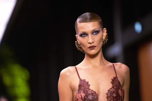 Bella Hadid verscheen op de catwalk van Saint Laurent met een ultrastrakke zijscheiding en een lekker donker, mysterieus make-up lookje. 