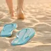 Vrouw loopt op blote voeten naast haar teenslippers.