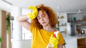 Portrait of young tired woman with rubber gloves resting after cleaning an apartment. Home, housekeeping concept.