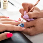 Woman getting her nails done in salon by manicure worker