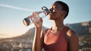 Black woman, runner and drinking water for outdoor exercise, training workout or marathon running recovery. African woman, healthy athlete and hydrate with bottle for fitness, health and cardio run