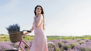 happy woman with bike and lavender flowers looking away in summer field.