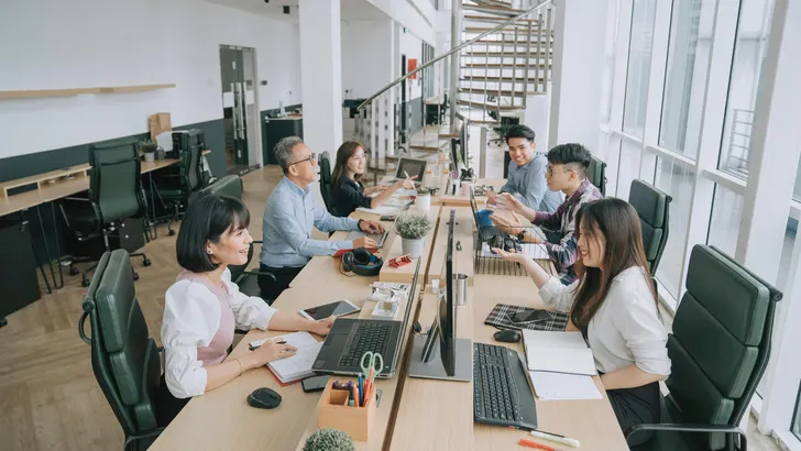 Asian multi-ethic white collar worker busy working and communicate in their office workstation in open plan cheerful and happily