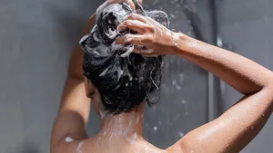 Vrouw die haar haren wast onder de douche