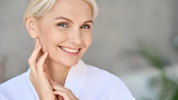 Portrait of smiling mid age woman looking at camera. Skin care concept.