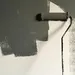 Verfroller met grijze verf op muur