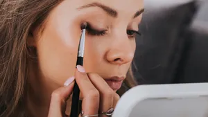 Close up portrait of beautiful young woman applying eyeshadow powder