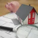 Beleggen in vastgoed. – Foto van miniatuur-huisje op plattegrond bij spaarvarken.
