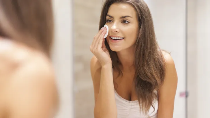 Beautiful brunette woman removing makeup from her face