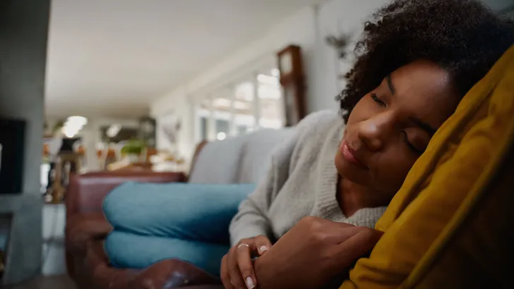 Tired african woman sleeping cozy on comfortable sofa at home