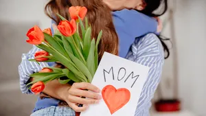 Kind geeft moeder bloemen en kaart voor moederdag