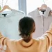 Vrouw houdt twee kledinghangers met kleding vast - permatrends -