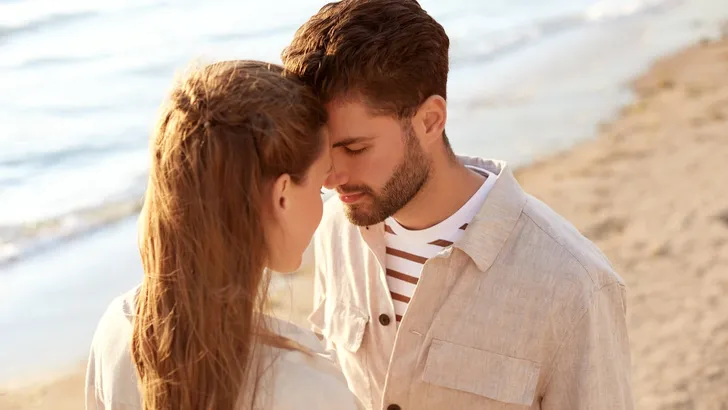 happy couple with closed eyes on summer beach