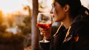 Young woman with a glass of red wine in sunset light at a terrace.