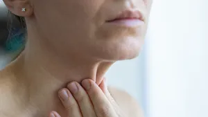 Vrouw pakt slappere huid in haar nek tussen vingers.