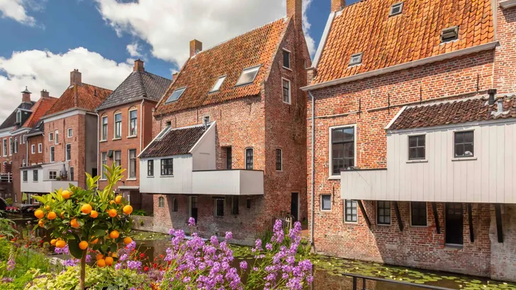 Summer view of Dutch medieval houses with hanging kitches at the Damsterdiep canal in Appingedam, Groningen, The Netherlands