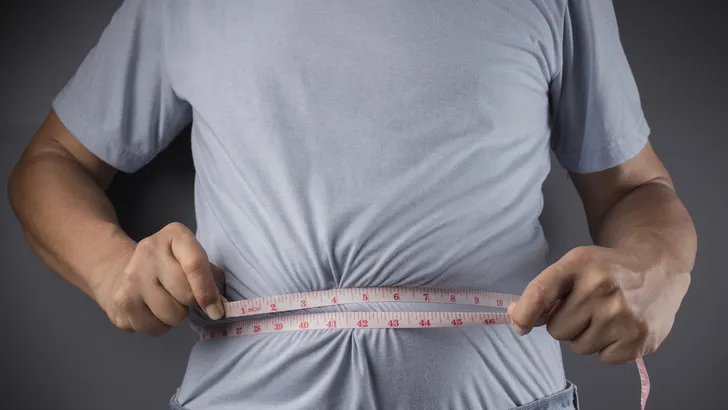 Man die zijn tailleomvang meet