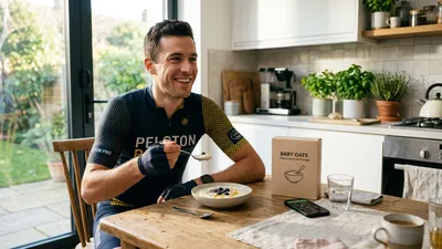 Mannelijke wielrenner zit in fietskleding aan de keukentafel zonder helm op en eet een kommetje gladde witte rijstepap als ontbijt.