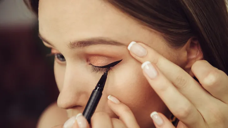 Woman doing makeup and painting black arrows
