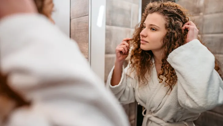 Young Woman Looking At Herself In The Bathroom Mirror