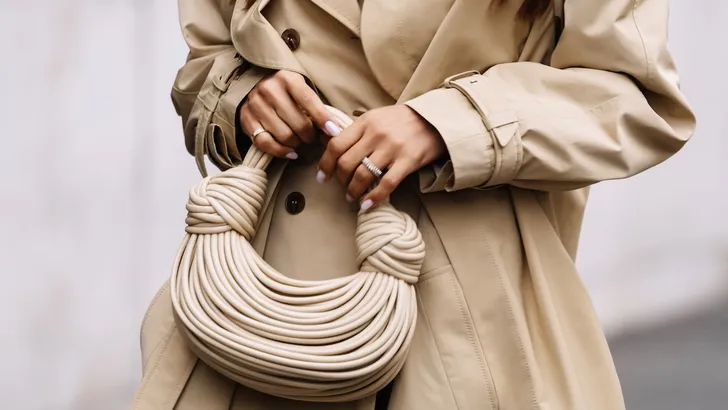 Weekendtips van Beau Monde – close-up foto van beige handtas en trenchcoat.