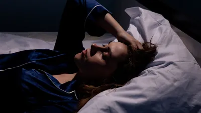 Vrouw zit slapeloos in bed.