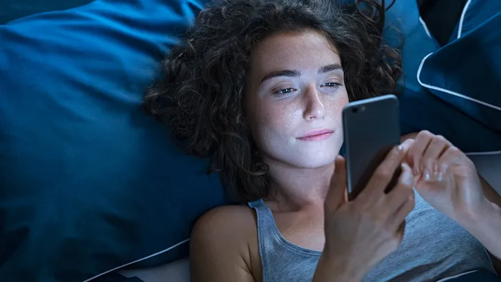 Girl awake in bed using cellphone at night