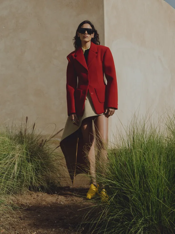 Wollen jasje, viscose trui, katoenen bloes, rok en schoenen: Loewe | Ringen: Zag Bijoux | Bril: Victoria Beckham 
