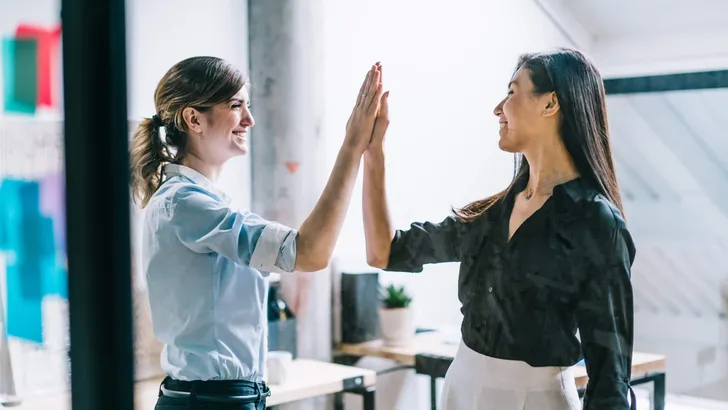Two professional positive colleagues celebrating success of team