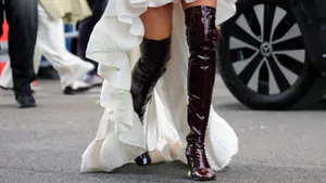 Streetstyle-foto van persoon tijdens Paris Fashion Week met kniehoge laarzen. Deze retro laarzen-trends maken in het najaar van 2025 een comeback.