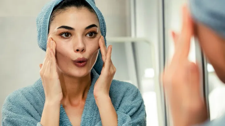 Een vrouw die face yoga aan het doen is in de spiegel