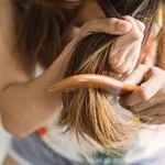 Woman combing tangled hair, Hair problems concept