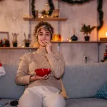 Woman watching movie and eating snacks at Christmas