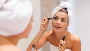 Mooie vrouw die mascara gebruikt in de badkamer