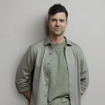 Simon Keizer vertelt over romantiek. – Foto van Simon Keizer tegen grijsgroene achtergrond.