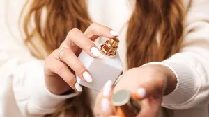 Foto van vrouw die parfum op pols spuit. Deze goedkope hack zorgt dat je parfum urenlang blijft hangen.