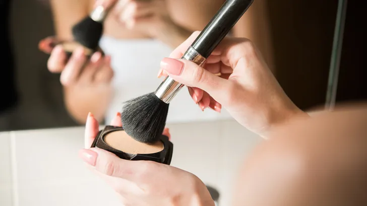 Close-up shot of a woman putting powder on a make-up brush