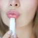 Close-up foto van vrouw met getuite lippen en lippenbalsem.