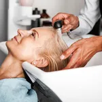 Hair stylist washing mature woman hair