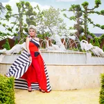 Foto van Marjan Strijbosch, bekend van The Real Housewives van het Zuiden, in een rode outfit bij een fontein.