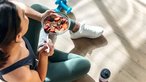 Athletic woman eating a healthy bowl of muesli with fruit sittin