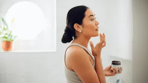 Morning Routine: Attractive Asian Woman Applying Face Cream in her Home
