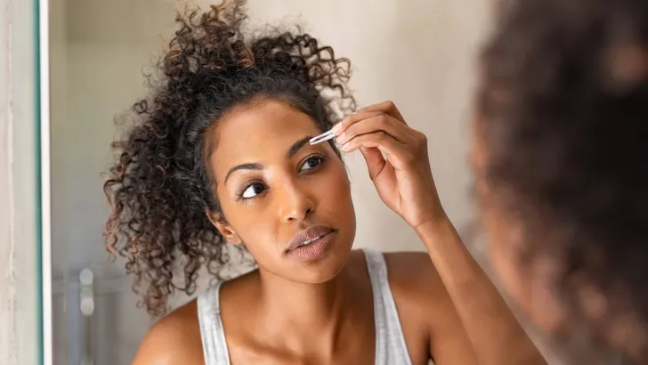 African woman plucking eyebrows