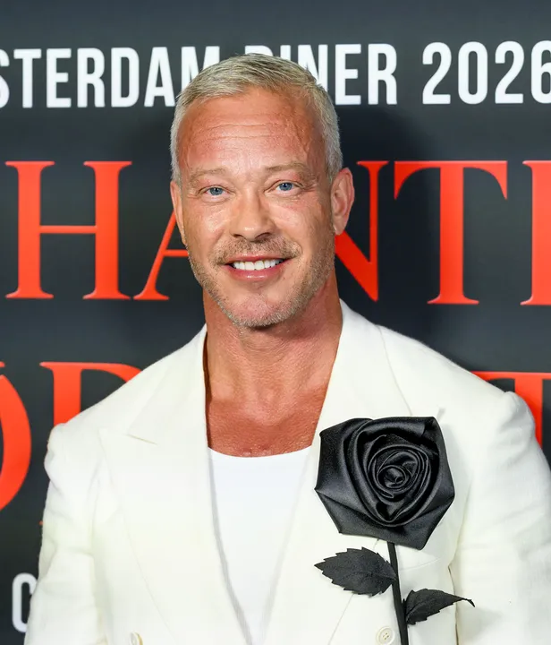 Claes Iversen in een wit pak met zwarte roos als corsage bij het Amsterdam Diner 2026 in AFAS Live