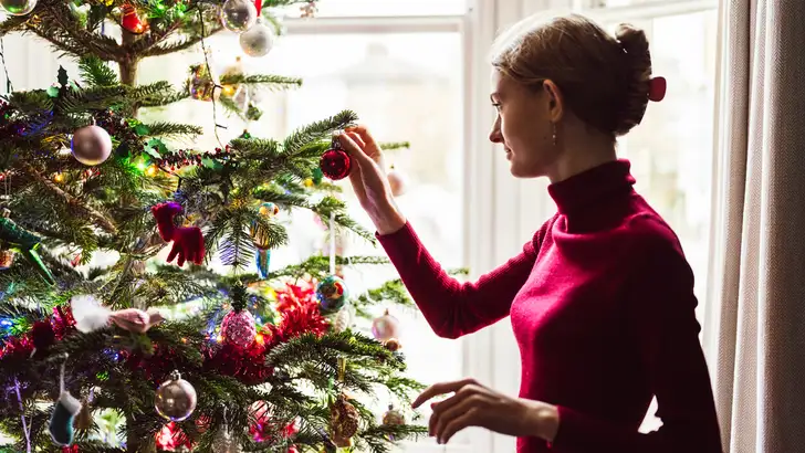 Teenage girl decorating traditional Christmas tree